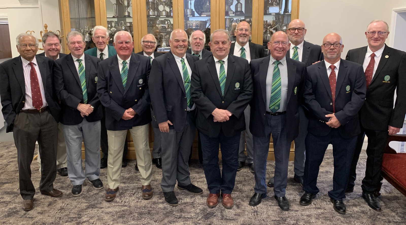 An inviting scene of senior golfers at Grimsby Golf Club, playing a round of golf together. Show them interacting on the green, with smiles and friendly banter. In the background, depict beautiful trees and clubhouse facilities.